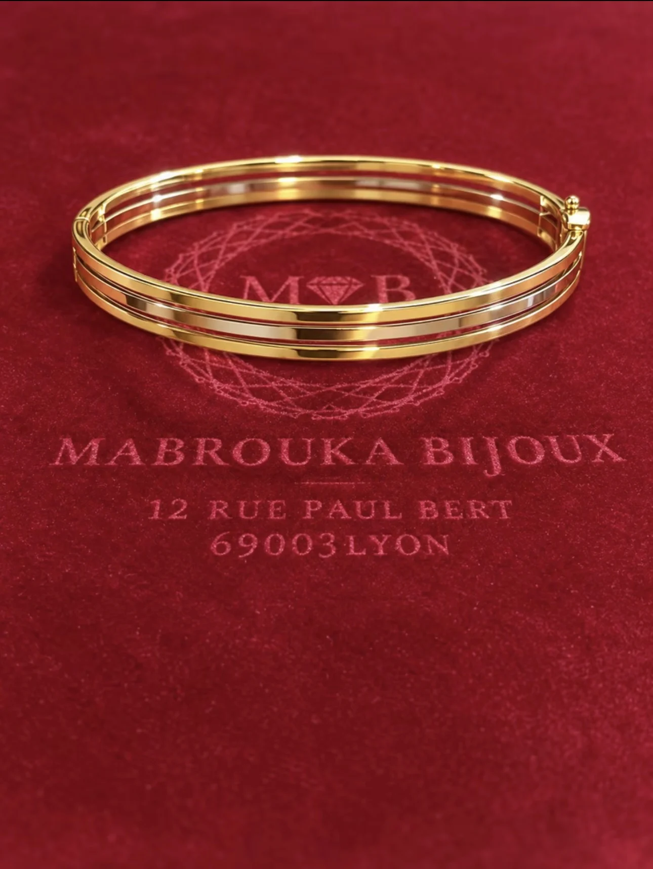 IMG_6048.webp Bracelet jonc Katarina trois ors 18 carats sur fond bordeaux Mabrouka Bijoux